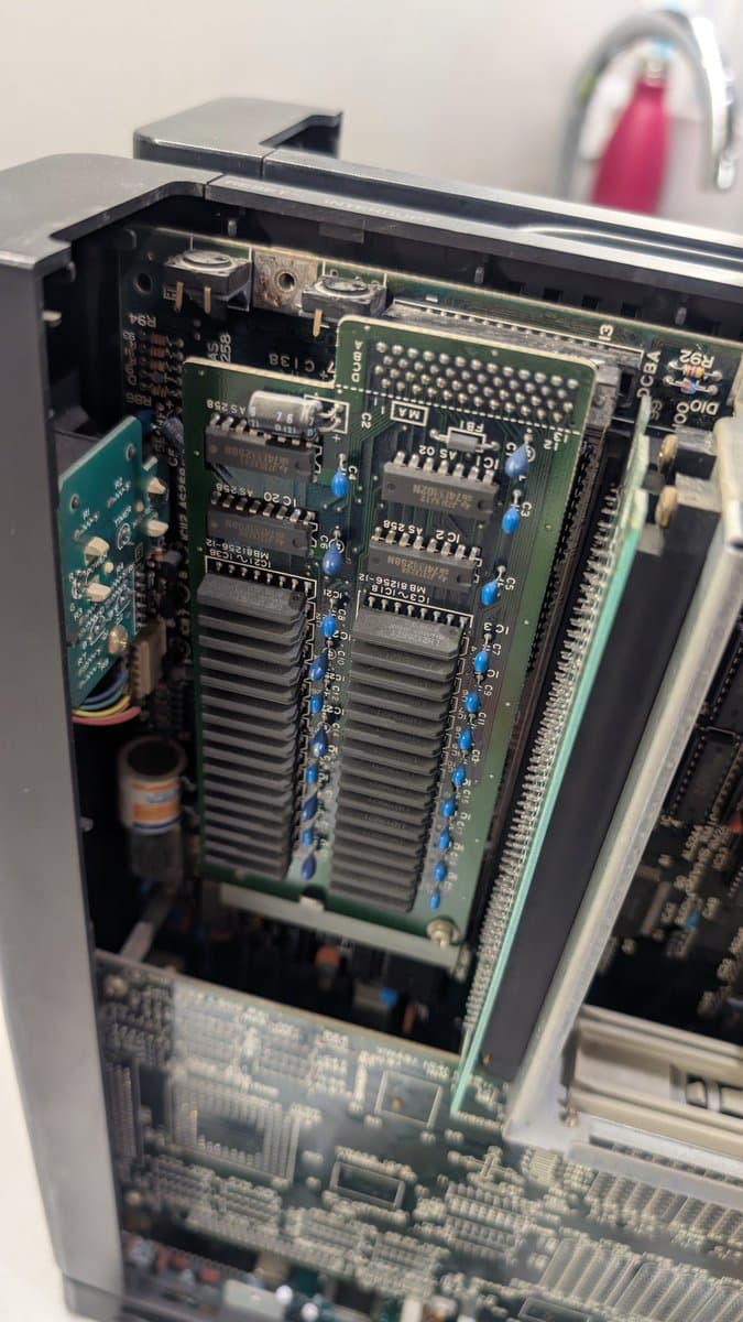 Sharp X68000 RAM expansion board loose inside chassis; multiple memory modules visible on green PCB with blue capacitors.