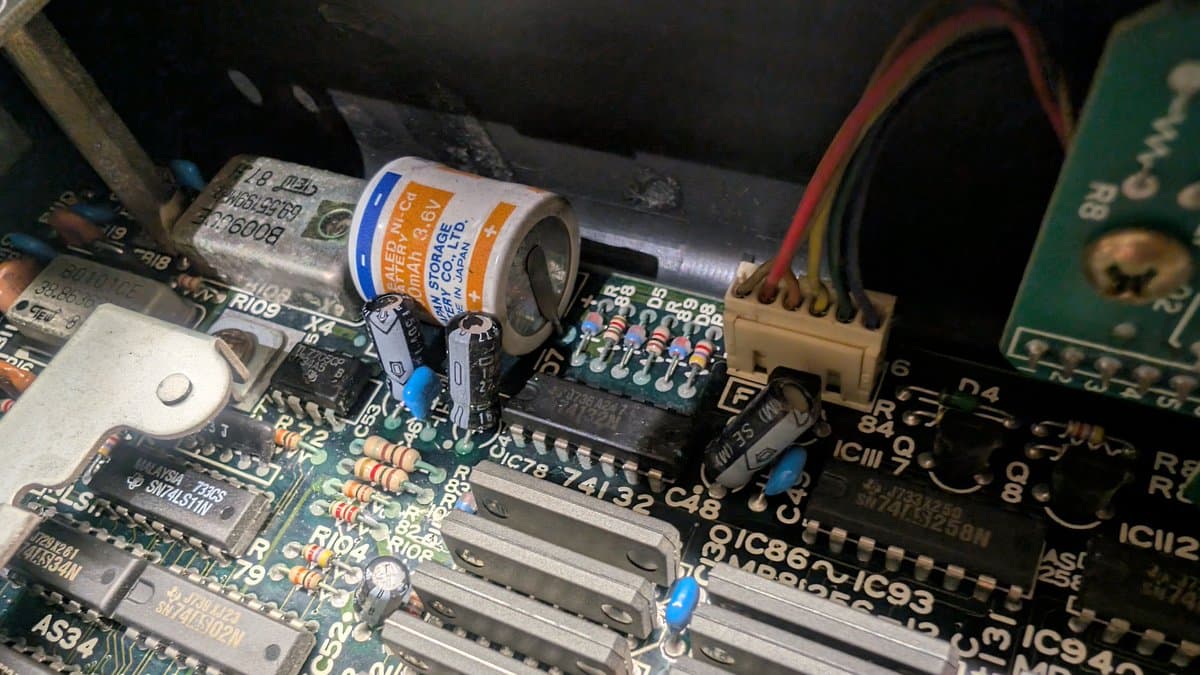 Battery-damaged circuit board with corrosion cleaned; tantalum capacitor visible above IC chips on Sharp X68000 motherboard during restoration.