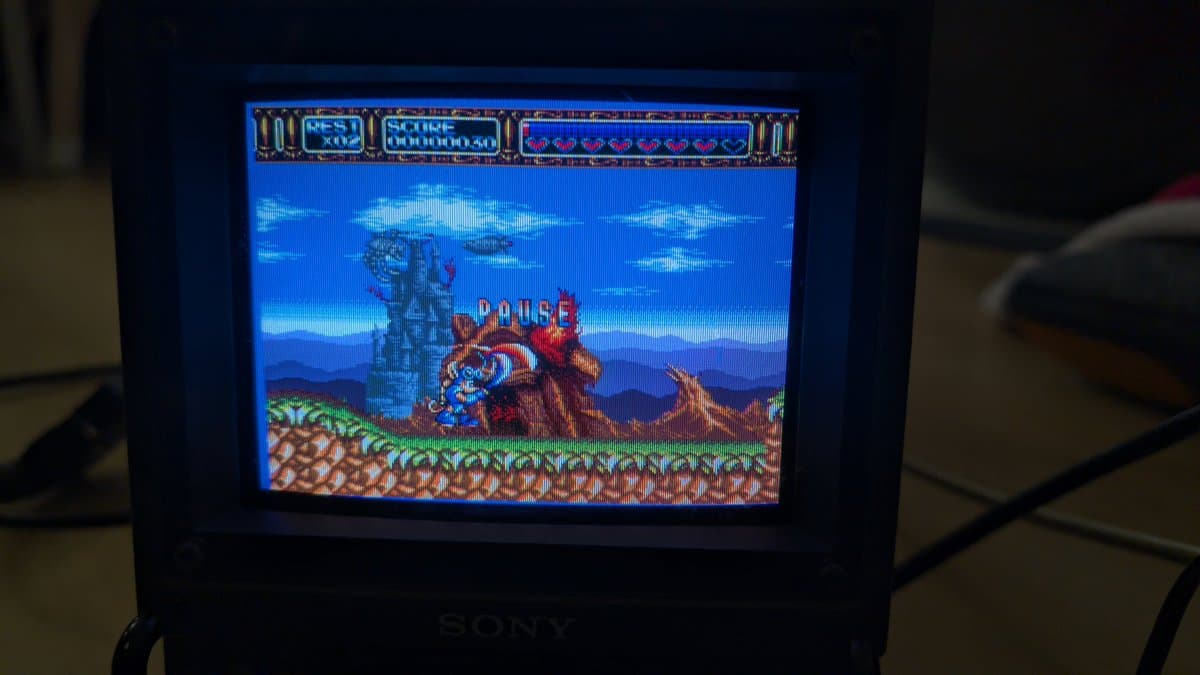 Sony PVM-6041Q displaying Rocket Knight Adventures RGB output from Sega Nomad; pause screen shows character on rocky terrain with blue sky background.