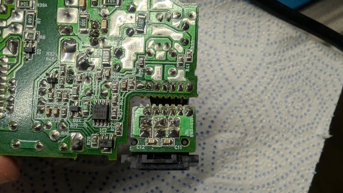 Close-up of N64 PSU board showing reflowed solder joints near power connector and capacitors after recap service.