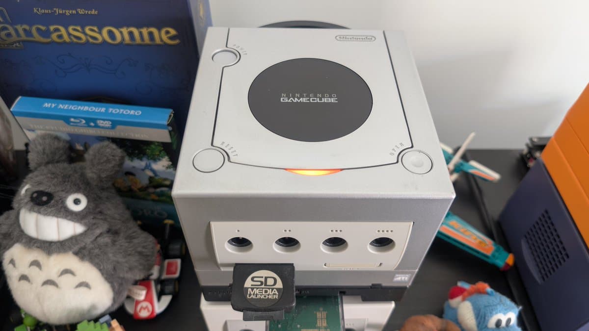 Silver Nintendo GameCube with SD Media Launcher installed, four controller ports visible, power LED lit during mainboard recap restoration project.