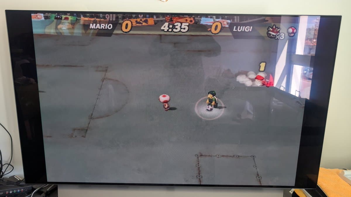 Mario Strikers match in progress on GameCube; Mario vs Luigi, 4:35 timer, score 0-0. Testing restored Pearl White DOL-001 board in DOL-101 shell after optical drive recap.