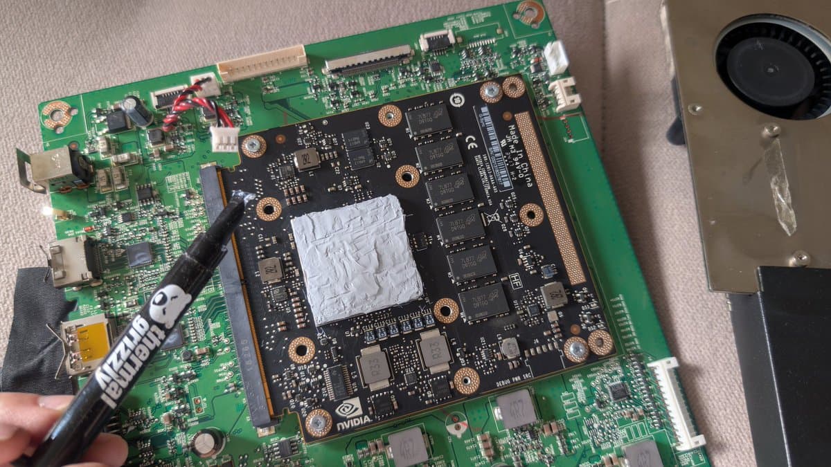 Asus PG27UQ mainboard with thermal paste applied to G-Sync module; recapping work visible on green PCB substrate.