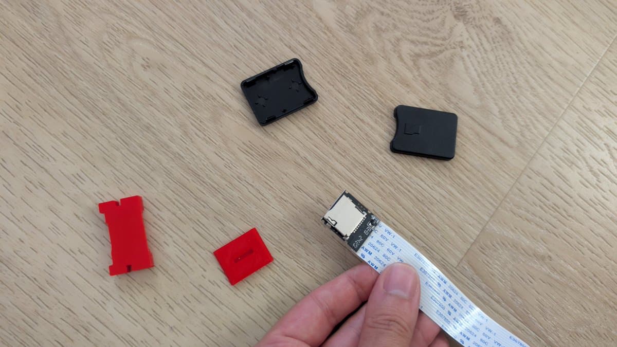 3D printed SD card extender parts in red and black plastic alongside ribbon cable and housing components for 3DO ODE mod installation.