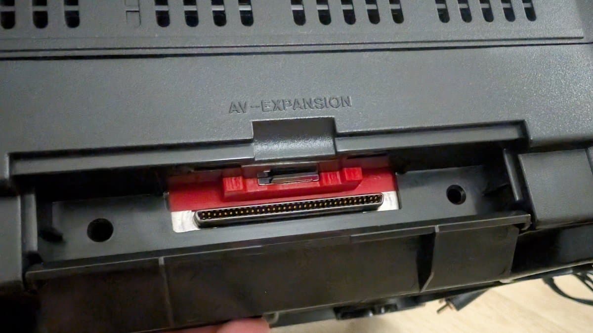 Panasonic FZ-1 AV expansion port with red connector carrier installed, showing parallel DB connector interface for game cartridge access.