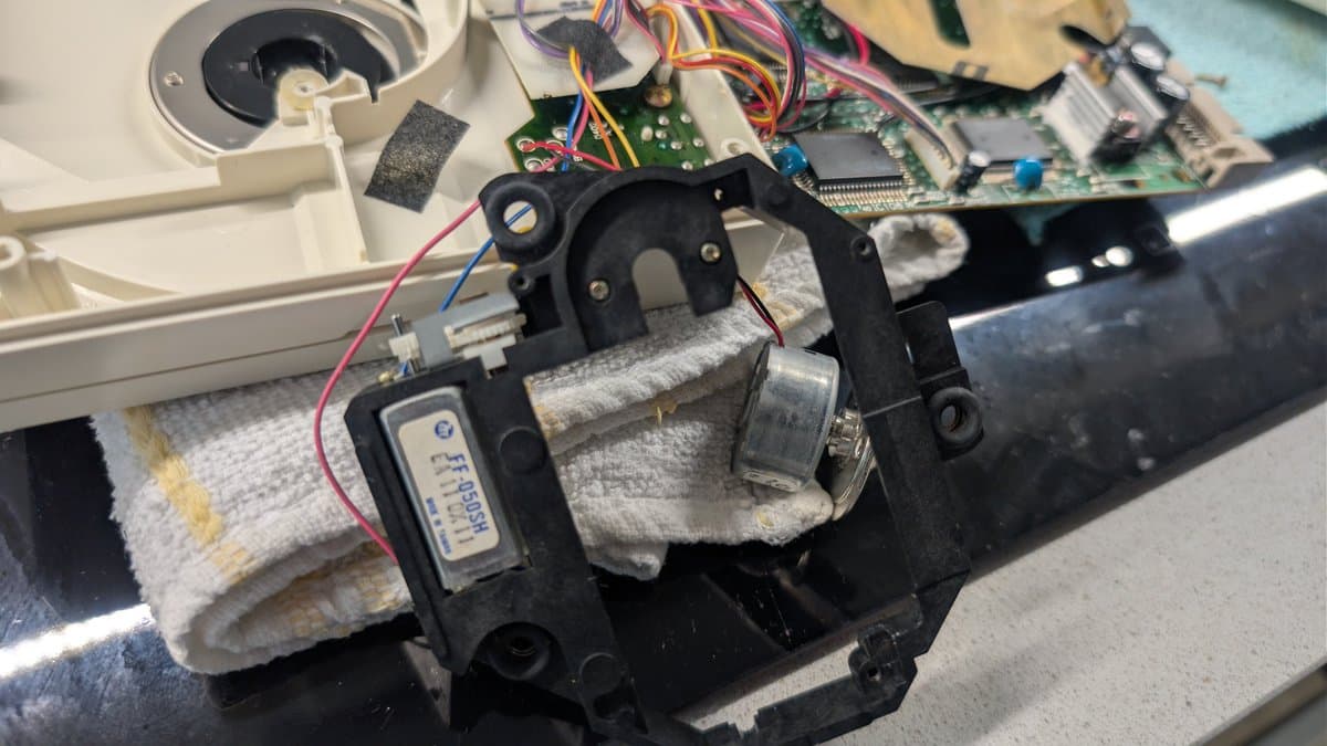 PC Engine CD-ROM2 spindle motor assembly with thermal insulation wrap, mounted bracket, and visible wiring during laser transplant procedure.