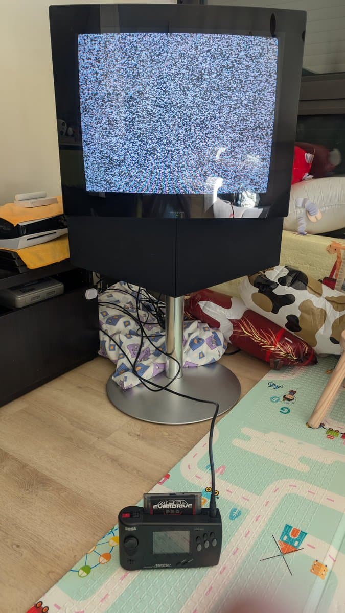 Bang & Olufsen Beovision 1 displaying blue static on screen, connected to Sega Genesis console, showing post-repair power-on test.